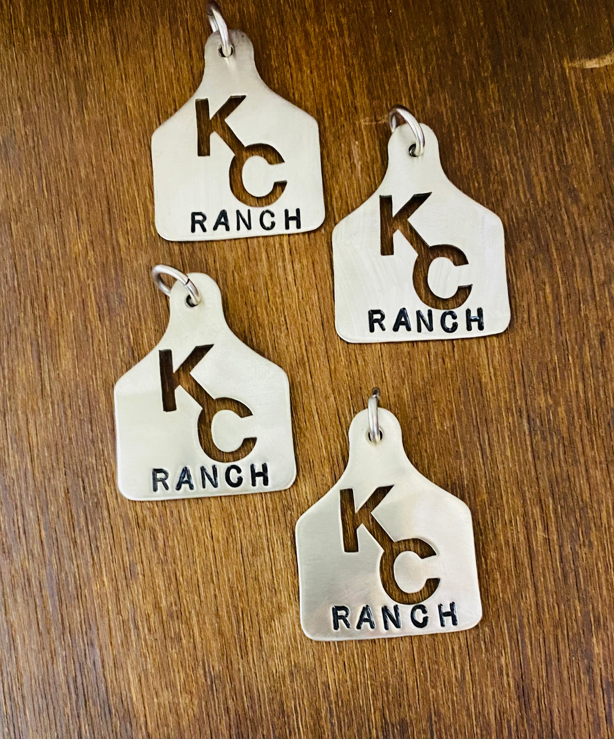 Four matching sterling silver ear tags with the KC Ranch brand, made for a ranch family