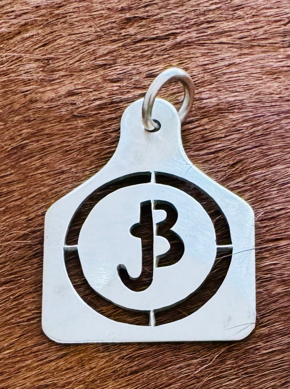 Sterling silver ear tag pendant with a JB ranch brand inside a circle, hand cut by Ambriz Jewelry