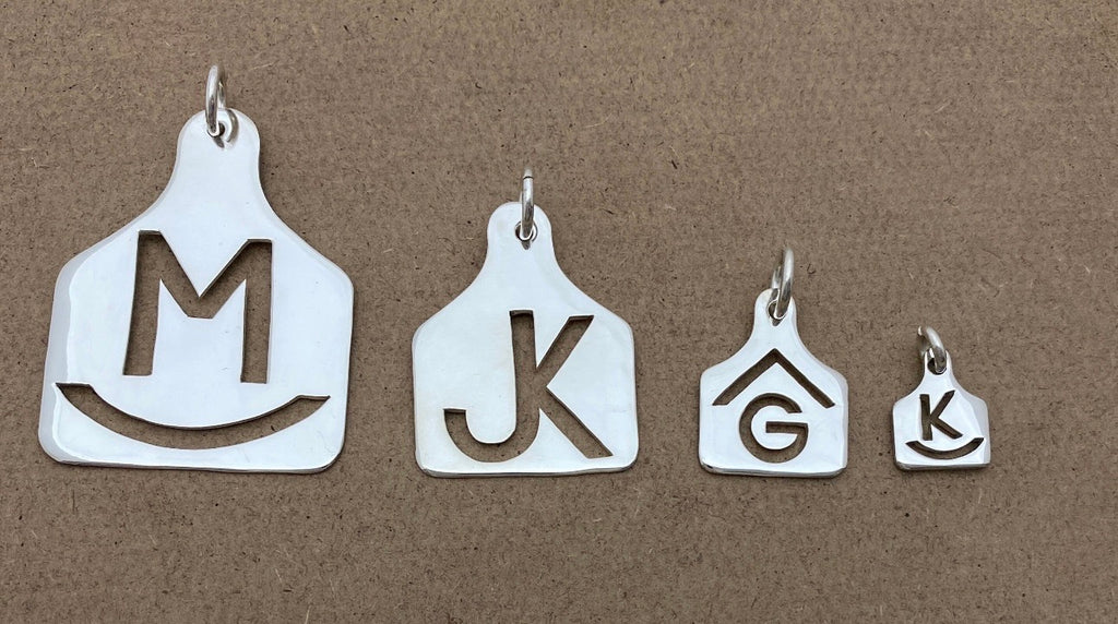 Four hand cut sterling silver ear tag pendants in Mini, Small, Medium and Large, with brands M, JK, G and K