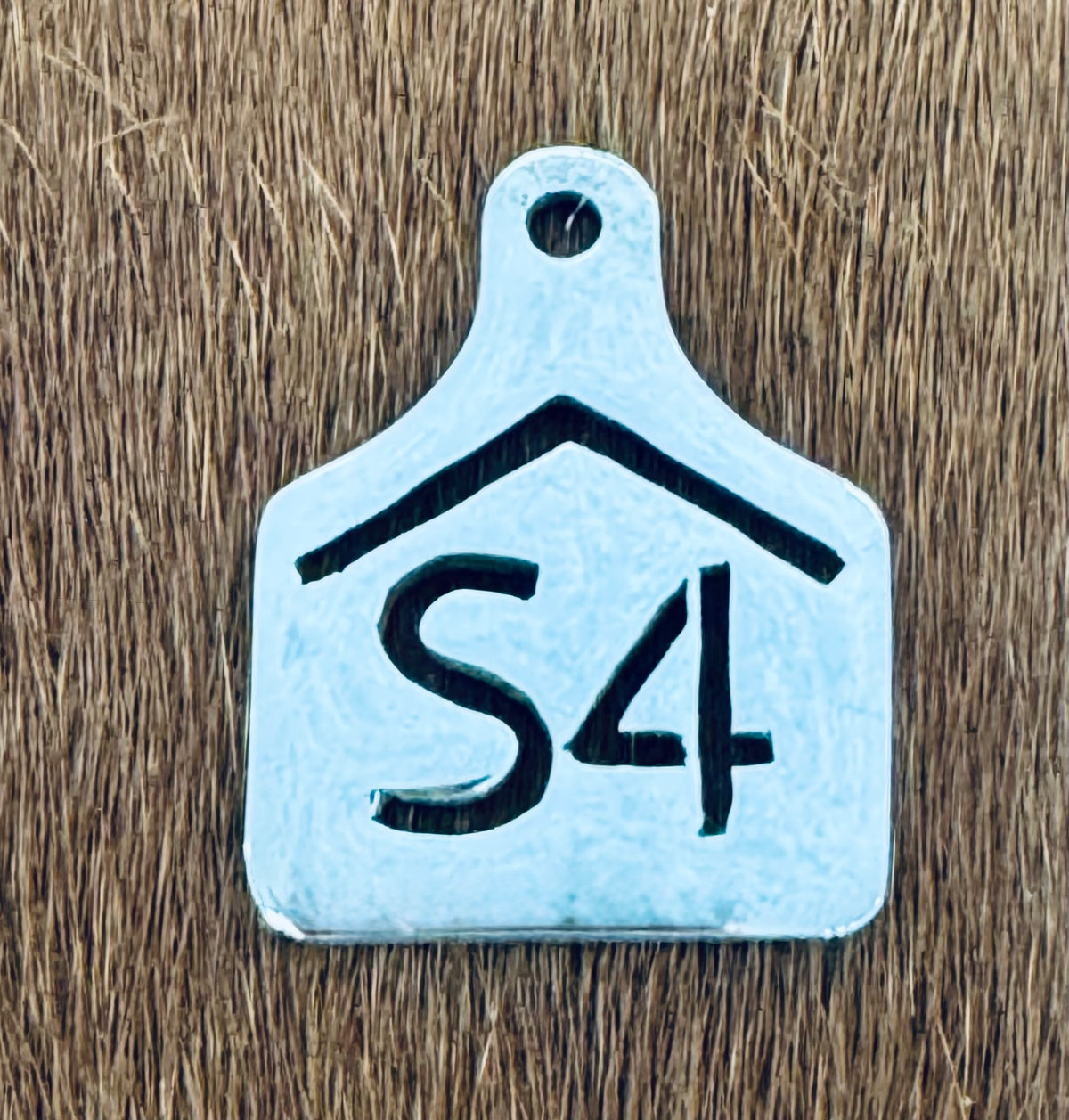 Hand cut sterling silver ear tag pendant with the S4 ranch brand, on cowhide